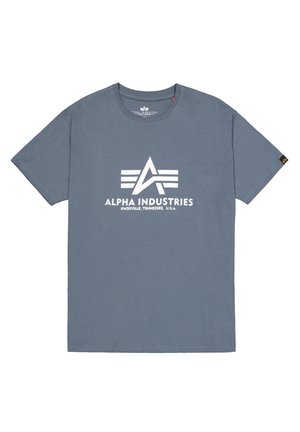 Camiseta de algodón gris con un logo blanco central que presenta el texto "ALPHA INDUSTRIES" y franjas horizontales. Diseño de manga corta y cuello redondo.
