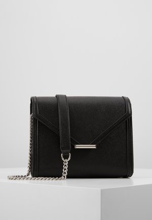 Zwarte crossbodytas van getextureerd leer met zilveren kettingriem en metalen stangdetail op de voorsluiting, weergegeven op een witte ondergrond.