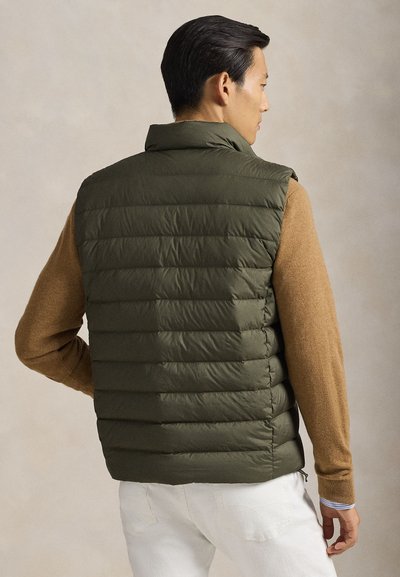 Olivengrønn dunvest med horisontal quiltet design, høy krage og ermeløs stil. Brukt over en brun genser med lange ermer.