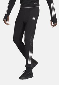 Zwarte sportbroek met drie verticale witte strepen aan de zijkanten en een getailleerd ontwerp. Gemaakt van een gladde, elastische stof.