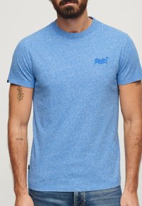Camiseta de algodón azul jaspeado de mangas cortas, con un cuello redondo y un pequeño logotipo bordado en el pecho.