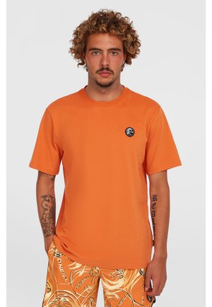Orange bomulds t-shirt med korte ærmer, rund hals, med et lille sort cirkulært logo på venstre bryst. Glat tekstur.