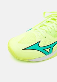 Bright yellow athletic shoe with mesh detailing, turquoise accents, and black lines. Designed for comfort and support during sports activities.