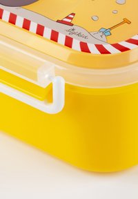 Gelbe Plastikbrotbox mit einem klaren Deckel, der ein Stranddesign und ein rot-weißes gestreiftes Muster am Rand des Deckels aufweist. Weißer Verschlussgriff.