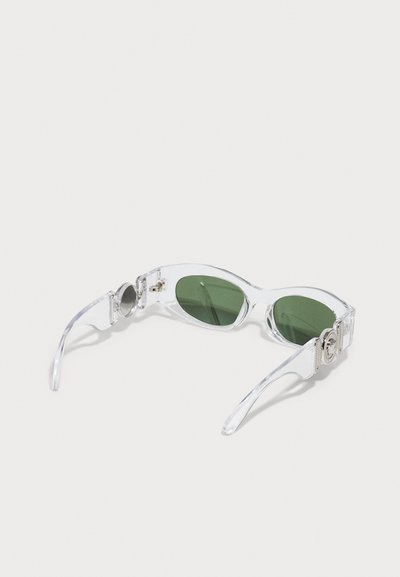 Ochelari de soare cu ramă clară, cu lentile verzi, de formă ovală sleek, având accente metalice pe brate și o textură netedă.
