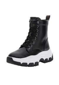 Bottines en cuir noir avec une semelle blanche épaisse, présentant un laçage et des accents en métal argenté. Intérieur texturé distinctif.