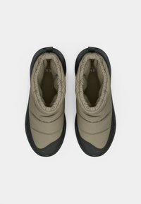 Kibővített bézs bokacsizma texturált fekete gumitalppal és elasztikus mandzsettával, minimalista dizájnnal és sima, tartós anyagból.