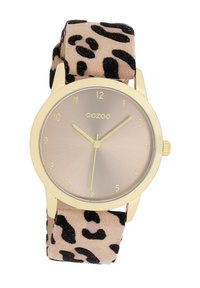 Montre dorée avec un cadran rond, un fond beige et des chiffres arabes noirs ; dotée d'un bracelet en tissu doux à motif léopard.