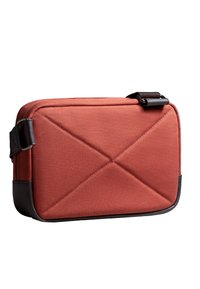 Borsa rettangolare in tessuto arancione bruciato con motivo a diamante trapuntato, con dettagli in pelle nera e tracolla regolabile.