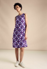Ärmelloses lila Kleid mit einem geometrischen Muster in verschiedenen Schattierungen von Blau und Pink. Weicher Stoff mit einem gerafften Ausschnitt, gerader Schnitt.