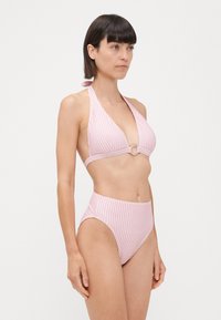 Costum de baie cu dungi roz și albe, cu sutien tip halter și un accent circular, având slipuri înalte. Țesătură fină, design minimalist.