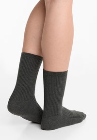 Donkergrijze geribbelde sokken van zacht materiaal, met een middenkuitlengte en een aangesloten elastische opening voor comfort en pasvorm.