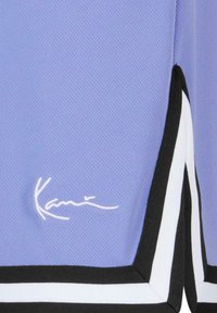 Lilla atletisk skjorte med tekstureret stof, sorte og hvide detaljer langs nederste kant og et hvidt broderet logo.