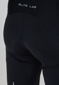 Leggings atletici neri con tessuto liscio, cuciture rinforzate e logo sulla vita. Design aderente con una sensazione senza cuciture.