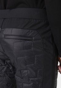 Czarne spodnie ocieplane z pikowanym wzorem w dolnej części oraz gładkim, elastycznym paskiem w talii. Posiadają kieszeń boczną z tyłu.