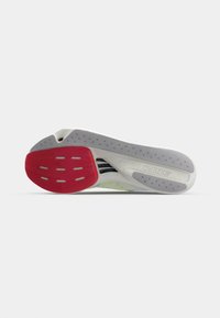 Semelle de chaussure de sport avec un design segmenté. Principalement blanche avec des accents gris et rouges. Présente une surface texturée pour une meilleure adhérence et des découpes à motifs.