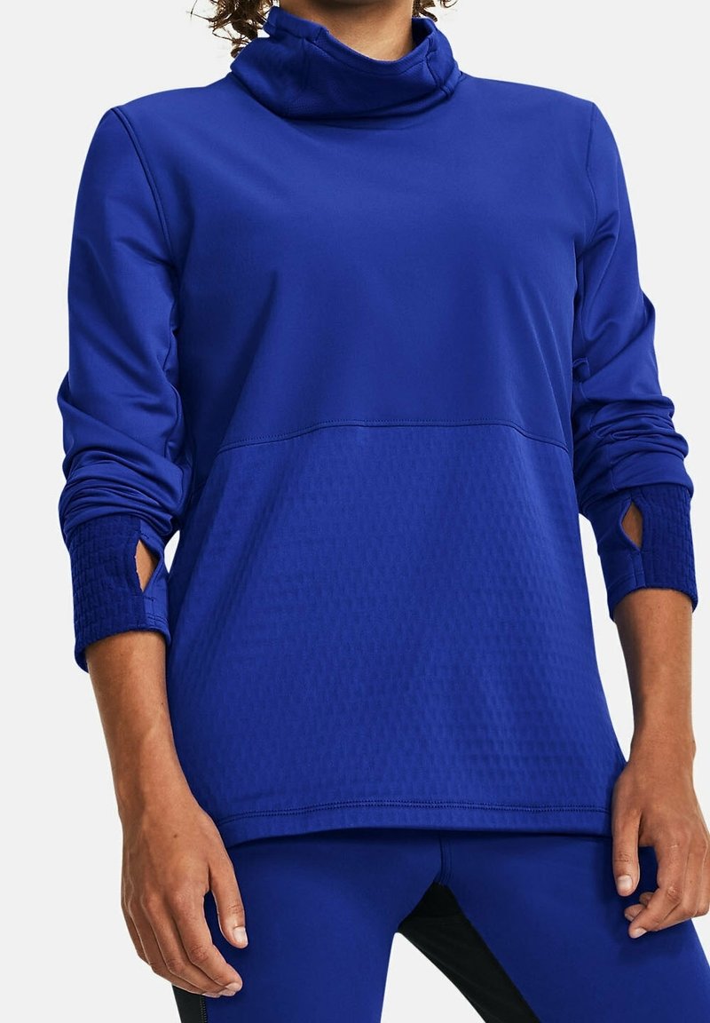 Haut de sport bleu à manches longues avec col montant, panneau inférieur texturé et découpes sur les manches pour les trous des pouces. Tissu lisse.
