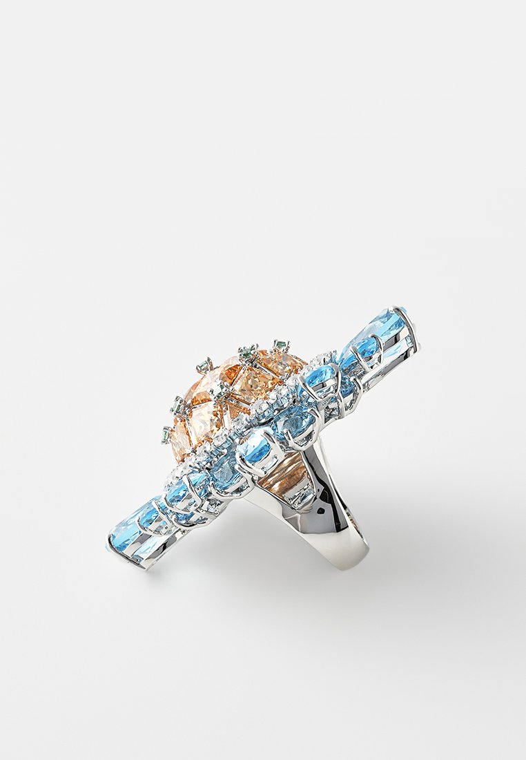 Bague en argent avec une rangée verticale de pierres précieuses bleu clair et un cluster central de pierres pêches et transparentes.
