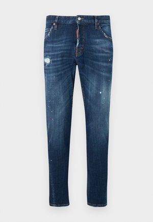 Dunkelblaue Jeans aus Denim mit schlanker Passform, versehen mit abgenutzten Stellen und Farbspritzern. Ausgestattet mit Standardtaschen und einem Knopfverschluss.