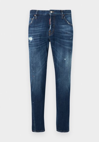 Jean en denim bleu foncé à coupe ajustée, présentant des zones usées et des éclaboussures de peinture. Fini avec des poches standards et une fermeture à boutons.