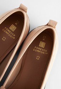 Pink synthetic leather ballet flats with a brown insole. Features embossed "FOREVER COMFORT" logo in gold and a small loop heel detail.