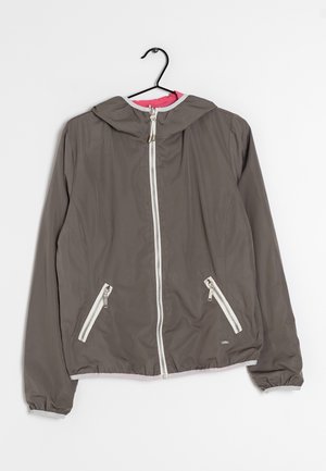 Šedá bunda s kapucí, předním zipem a dvěma zipovými kapsami, zavěšená na černém ramínku na bílém pozadí.