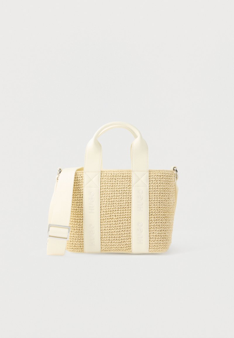 Petit sac fourre-tout tissé beige avec poignées en cuir crème et bandoulière réglable sur fond blanc.