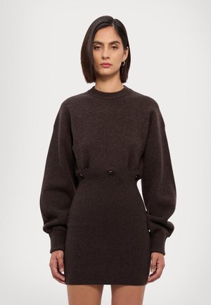 Tmavohnedé šaty so svetrom s vysokým golierom, objemnými rukávmi a rebrovanou textúrou. Ozdobené dvoma gombíkmi v páse.