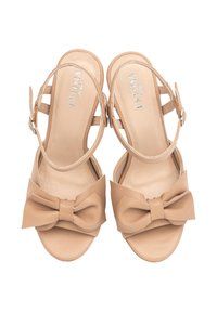 Beżowe skórzane sandały z okrągłym noskiem, regulowanym paskiem na kostkę i dużą kokardą na wierzchu. Gładka tekstura i minimalistyczny design.