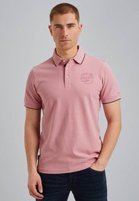 Polo rose clair en coton doux, avec une bordure de col noire, une patte de boutonnage à trois boutons, des manches courtes et un logo brodé sur la poitrine.