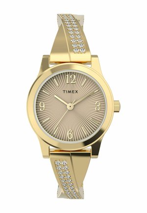 Montre-bracelet dorée avec un cadran beige strié, de grands chiffres arabes et un bracelet décoratif avec des cristaux transparents d'un côté.