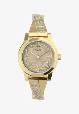 Montre-bracelet dorée avec un cadran beige strié, de grands chiffres arabes et un bracelet décoratif avec des cristaux transparents d'un côté.