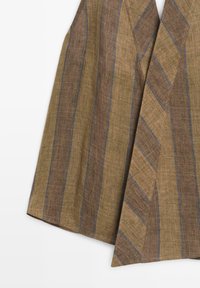 Brunt og beige stribet vævet stof med tynde blå lodrette striber, der viser detaljeret tekstur og overlappende folder.