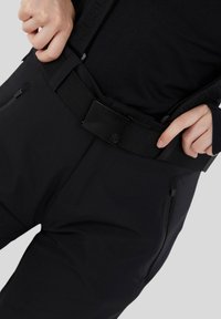 Schwarze technische Hose mit einem robusten Bund, verstellbarem Gürtel und Reißverschlusstaschen; glatte, matte Oberfläche mit minimalen Details.