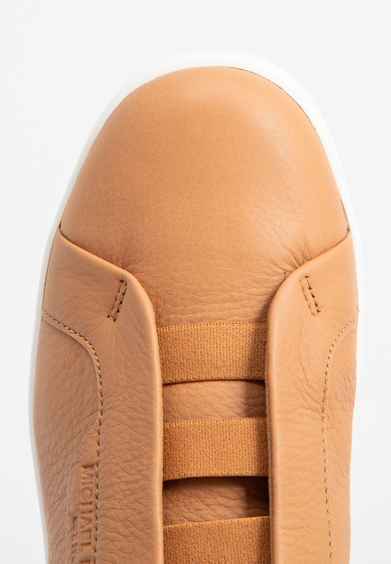 Baskets en cuir tan avec un bout arrondi, des sangles élastiques et une surface texturée. La semelle en caoutchouc blanche accentue le design.