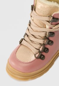 Ρ�οζ και ακανόνιστο μπεζ ορειβατικό μποτάκι με μπεζ κορδόνια, μεταλλικές θηλιές και παχύ ελαστικό πάτο.