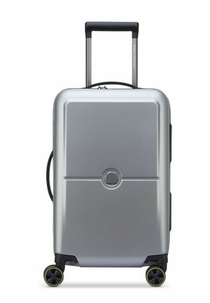 Silver hard-shell suitcase with a textured finish, retractable handle, and four black wheels with yellow accents. Circular logo on front.