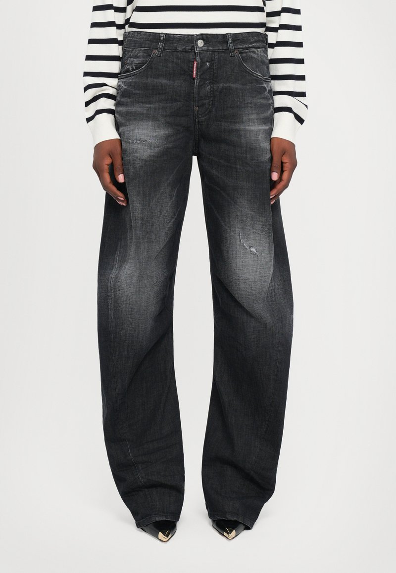 Wide-leg, dark gray denim jeans with faded details, pockets, and subtle distressing. Paired with a black-and-white striped sweater.