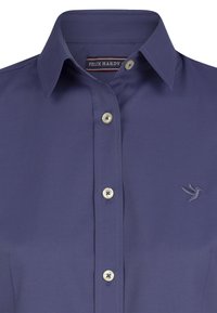 Camicia blu navy con colletto a punta, dotata di cinque bottoni chiari e un logo di un uccello ricamato sul lato sinistro del petto.