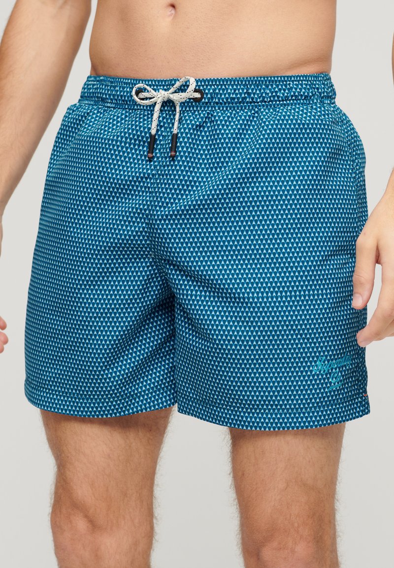Blauwe zwemshorts met een geometrisch patroon, elastische tailleband, koordsluiting en zijzakken.