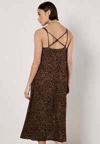 Brązowa midi sukienka w leopardzi wzór z cienkimi ramiączkami. Posiada krzyżujące się plecy i zwiewną teksturę.