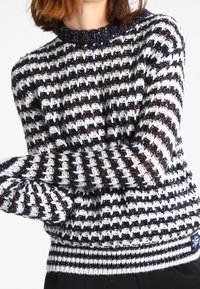 Pull en tricot avec un motif à rayures bleu marine et blanches orné d'accents métalliques. Encolure ronde et poignets ainsi qu'ourlet côtelés pour une texture supplémentaire.