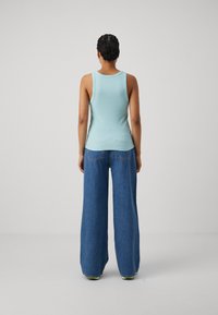 Lyseblå ribbet tanktop kombinert med vide blå jeans. Tanktoppen har rund halslinning, og jeansene har en klassisk denim tekstur.