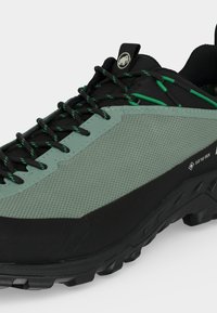 Υπαίθριο παπούτσι πεζοπορίας με επάνω μέρος από διχτυωτό υλικό σε μέντα πράσινο, μαύρη σόλα, μαύρα και πράσινα κορδόνια και σήμανση Gore-Tex στο πλάι.