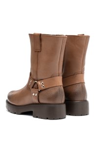 Brązowe skórzane botki za kostkę o teksturowanym wykończeniu, z klamrą i metalowymi akcentami oraz masywną brązową gumową podeszwą.
