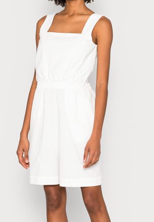 Valkoinen hihaton haalari, jossa on neliönmuotoinen pääntie, joustava vyötärö ja shortsit. Valmistettu kevyestä, sileäpintaisesta kankaasta.