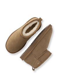Bruna mockalädersankel boots med en mjuk foder, rund tå och dekorativ sömnad. Har en liten dragtab och gummisula.