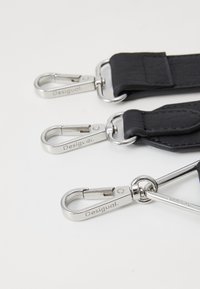 Zwarte banden met zilverkleurige hardware, voorzien van sluitclips en gemarkeerd met "Desigual." Glad oppervlak met gebogen en rechte randen.
