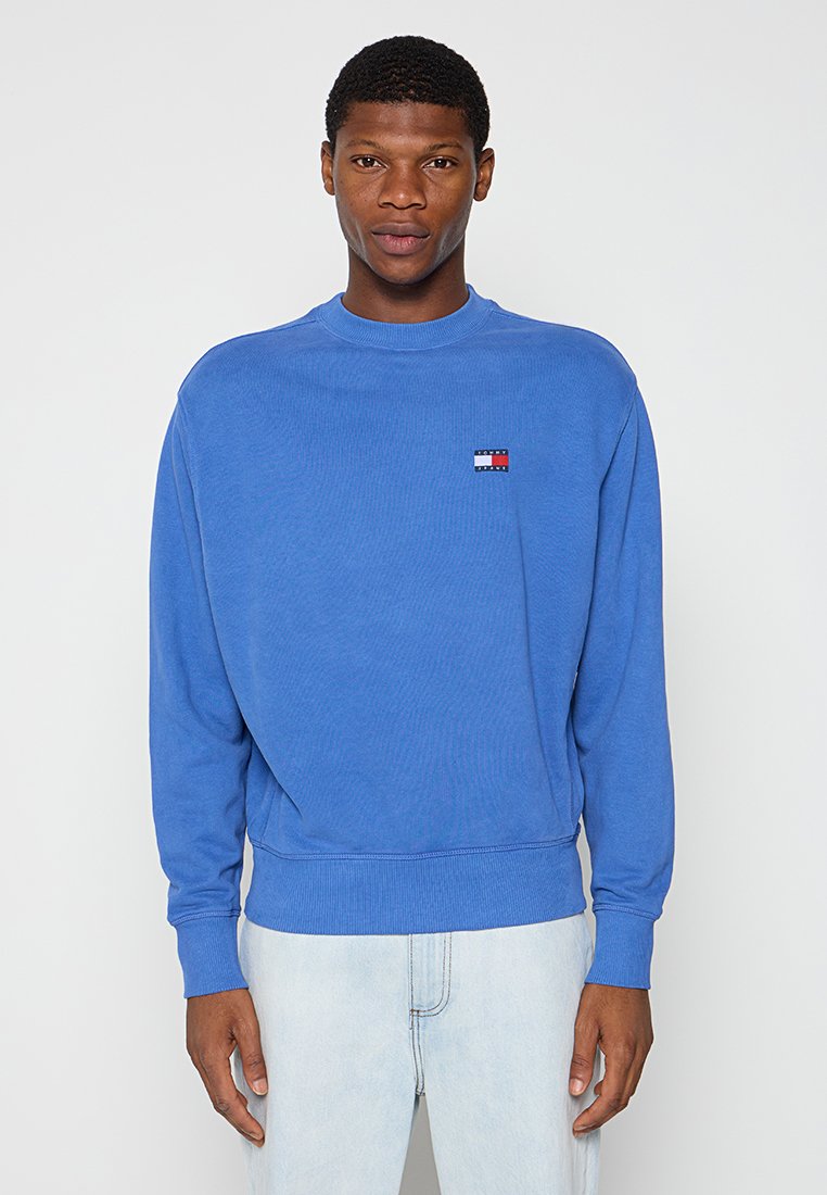 Błękitny sweatshirt wykonany z bawełny. Posiada okrągły dekolt, długie rękawy, ściągacze na mankietach oraz małą naszywkę z logo na klatce piersiowej.