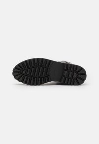 Suela de zapato de goma negra con un patrón de profundidad. Presenta una entresuela suave y bordes redondeados para una mejor tracción y durabilidad.